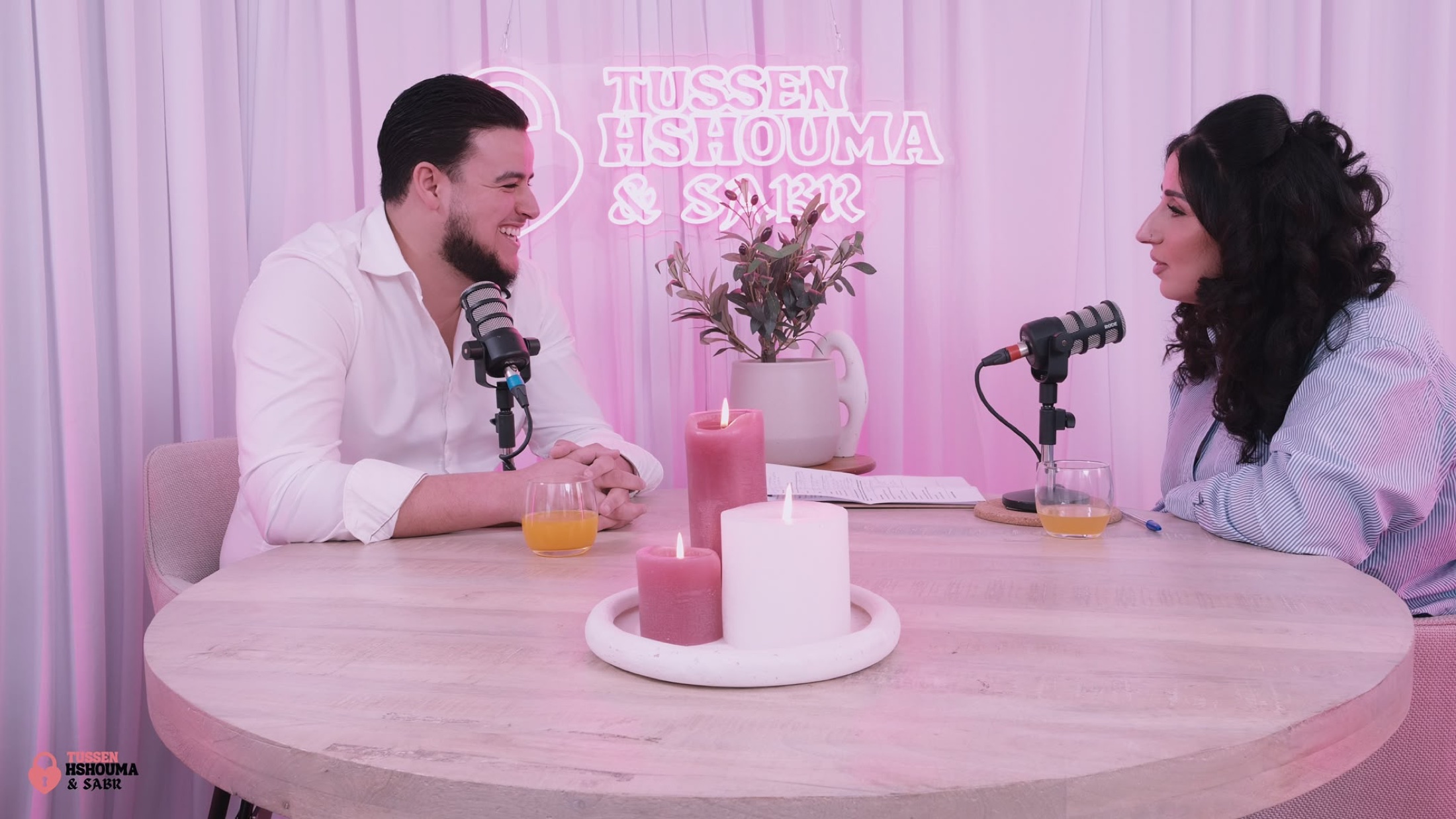 Podcast host and smiling guest at the pink studio table